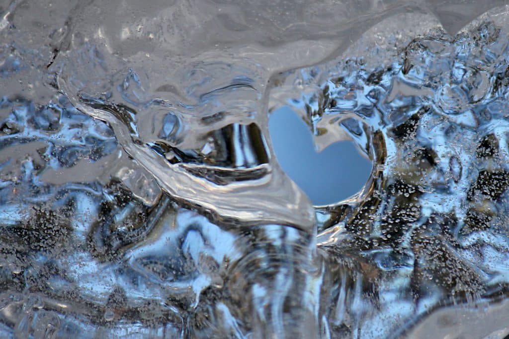 Jäätynyt vesi, jonka keskelle on sulanut sydämenmuotoinen aukko.